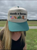 Person wearing a cap with 'Thank a Farmer' text and symbols in an outdoor setting