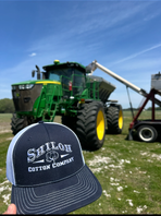 Tractor in a field with a person holding a cap labeled 'Shiloh Cotton Company'.