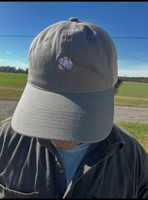 Person wearing a gray cap with a logo outdoors on a sunny day